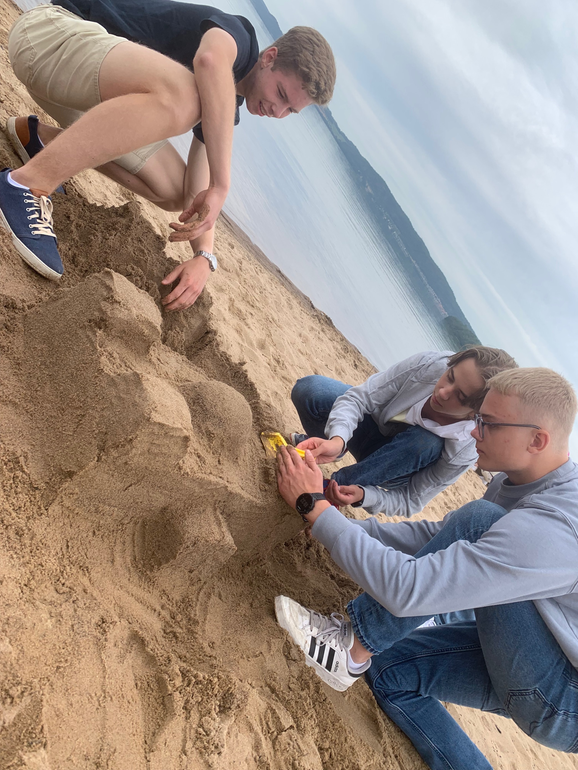 tre elever som bygger sandslott på vätterstranden.
