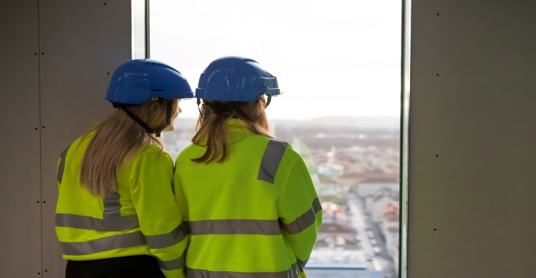 Två elever fotade bakifrån som tittar ut genom ett fönster.