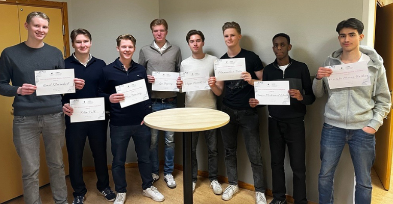 Åtta manliga elever som tittar i kameran och håller uppe sina vinster i FEST.
